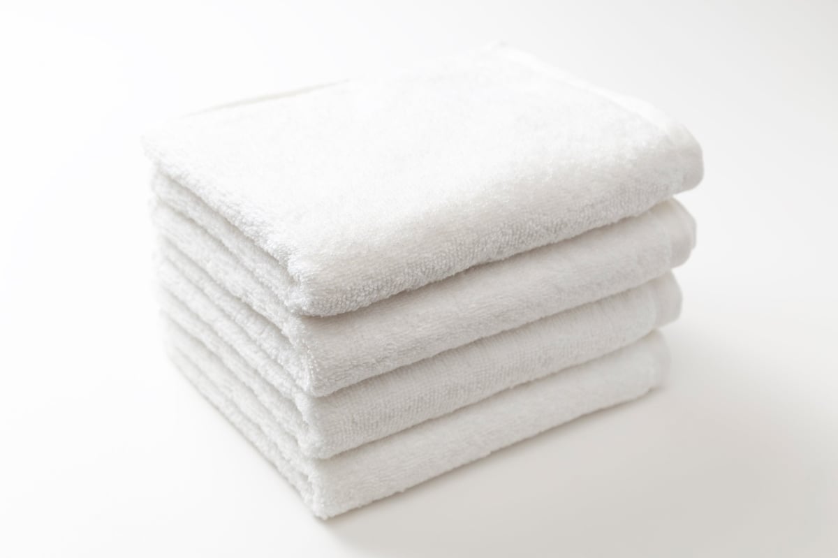 Neatly folded fresh white towel on a clean blue background